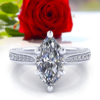 Vintage marquise cut moissanite engagement ring laying in front of red rose.
