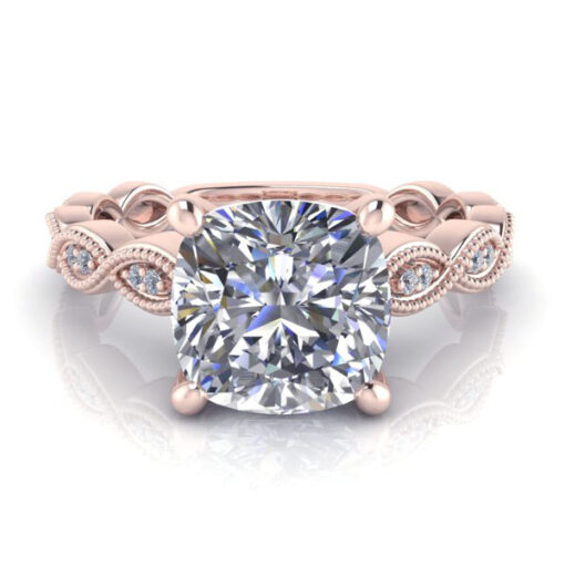 Vintage rose gold moissanite ring with cushion cut gem laying on flat surface.