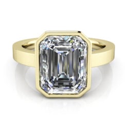 Emerald cut solitaire bezel set ring in yellow gold.
