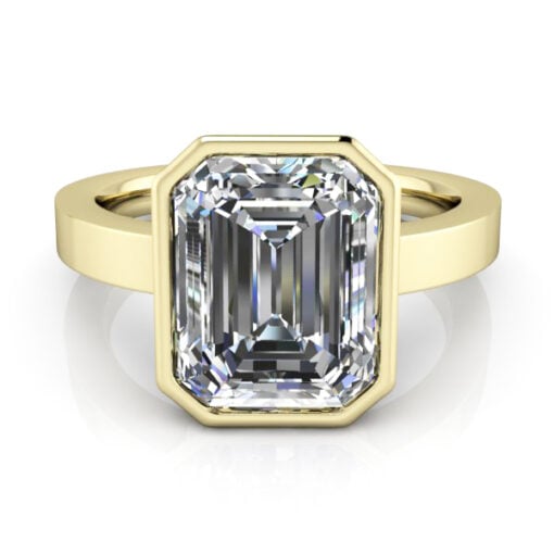 Emerald cut solitaire bezel set ring in yellow gold.